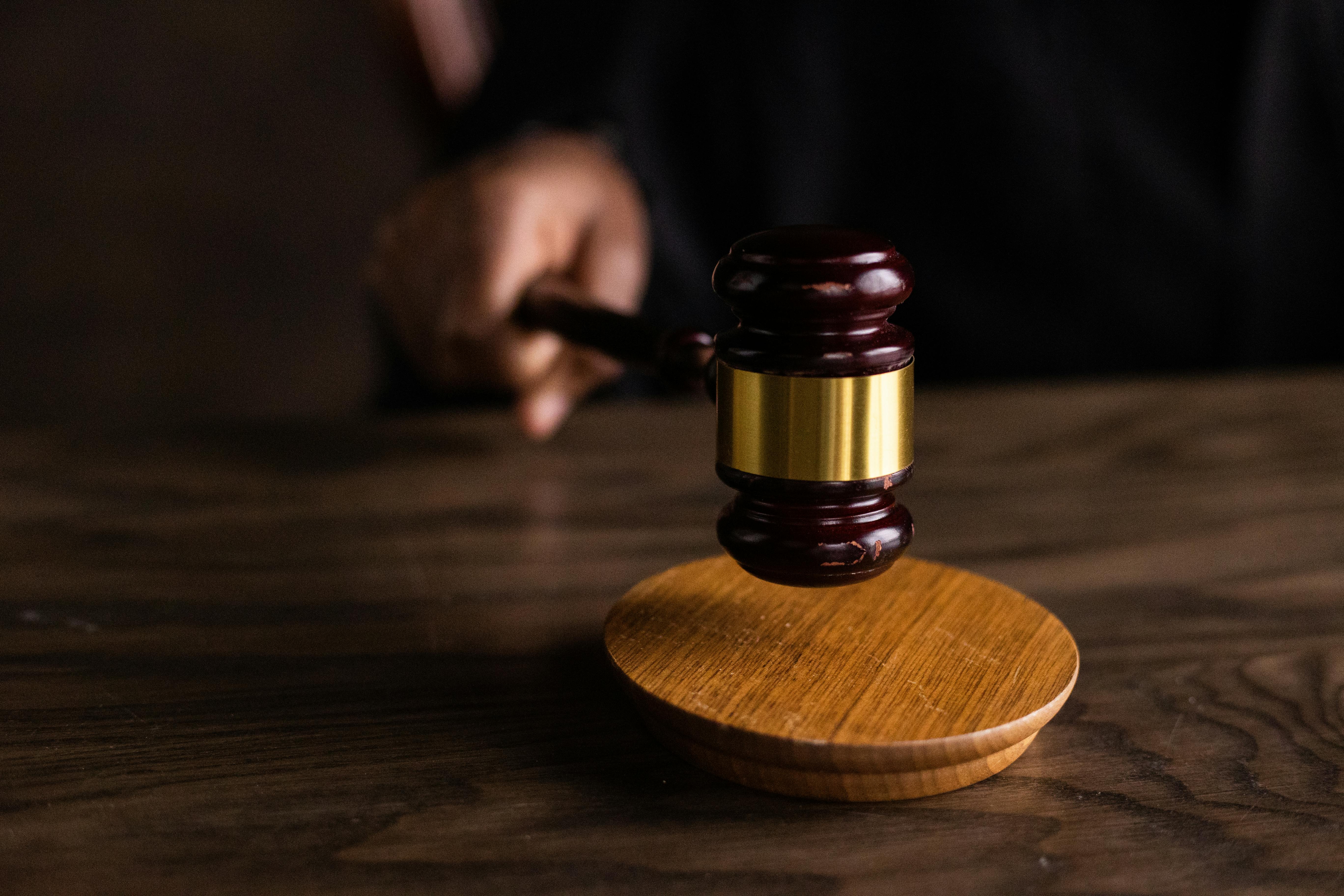 judge holding a brown gavel on a wood table